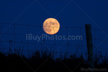 Pleine Lune derrière une clôture avec un poteau