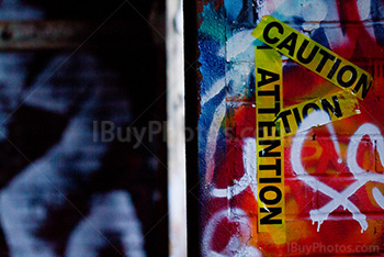 Yellow caution tape on wall covered by graffiti beside doorway