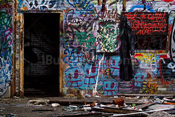 Dirty coat hanging in demolished house, with doorway and graffiti