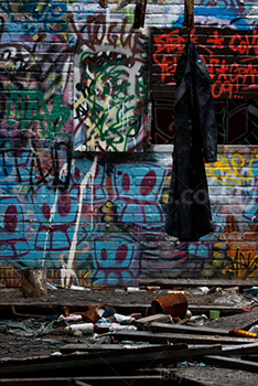 Dirty coat hanging in demolished room with graffiti on wall