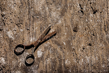 Old rusty scissors on wooden floor with dust