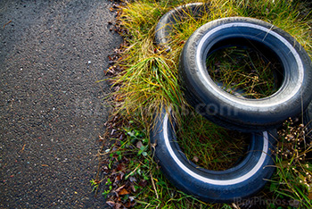 Pneus entassés dans herbe et asphalte