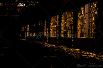 Broken windows and glass in abandoned building with light from street