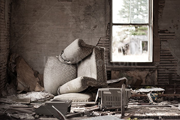 Chambre de maison abandonnée avec fauteuil renversé et mobilier cassé