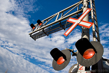 Railway crossing signals and lights at barrier with cloudy sky