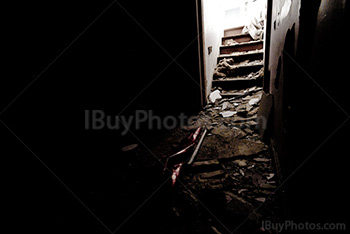 Escaliers lumineux dans salle sombre de maison abandonnée