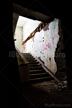 Lumière en haut d'escaliers sombres dans bâtiment délabré