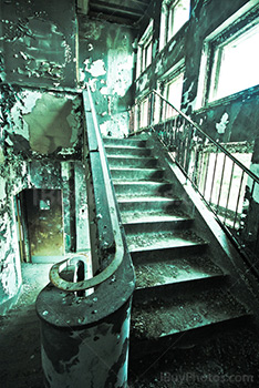 Creepy stairs in abandoned asylum with light from windows