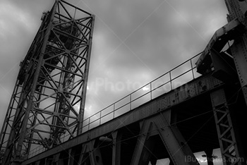 Metal tower structure with steel beams bridge with cloudy sky