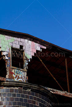 Broken window and crumbling wall with graffiti on top of factory silo