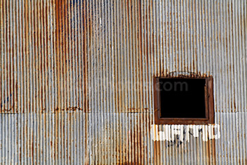 Old window on rusty corrugated iron plates